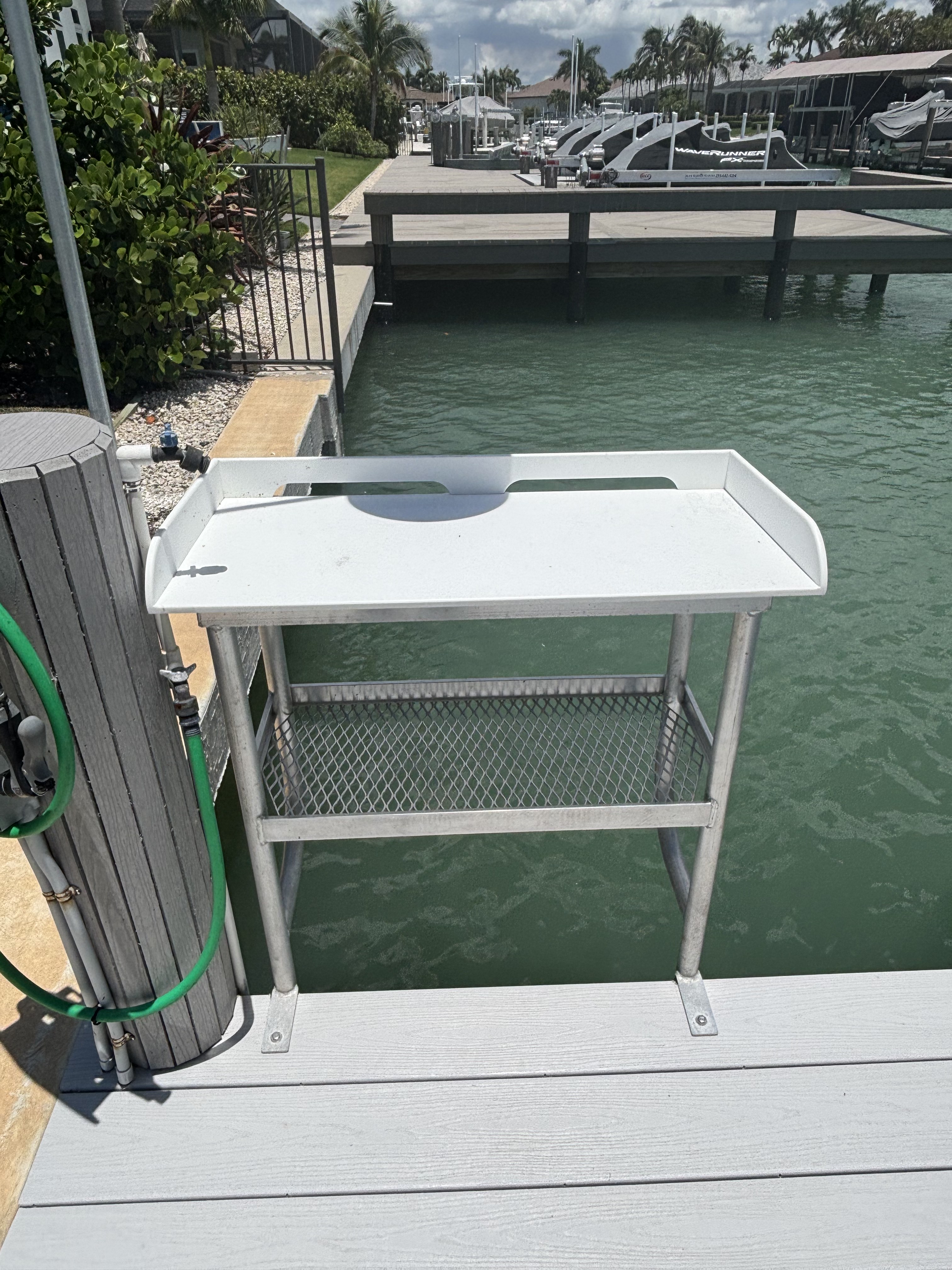 Fish fillet table with running water and aluminum legs, mounted at the dock edge.