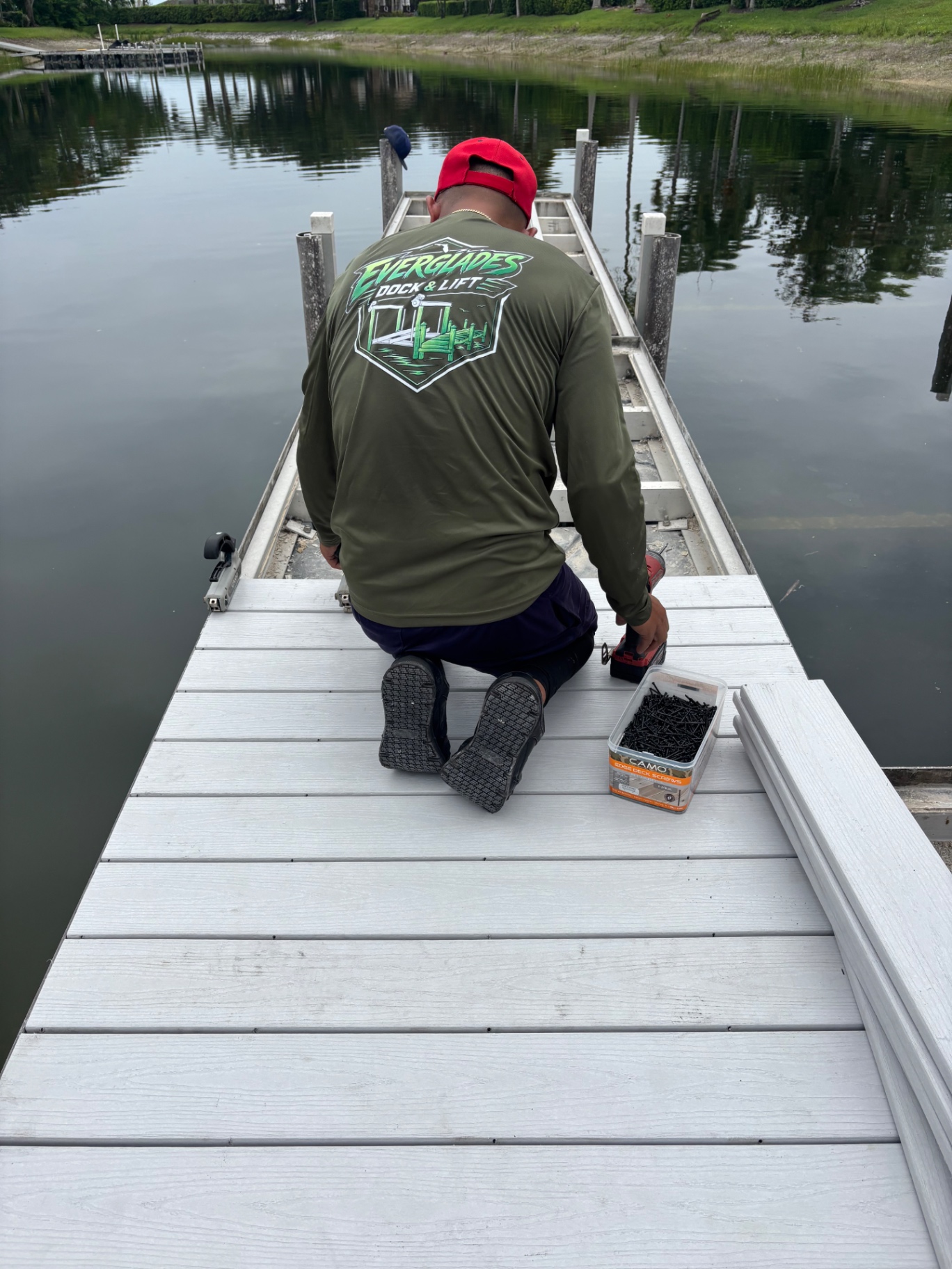 Crew installing new composite decking with CAMO hidden edge deck screws — no visible fasteners on top, tight consistent gaps between boards.