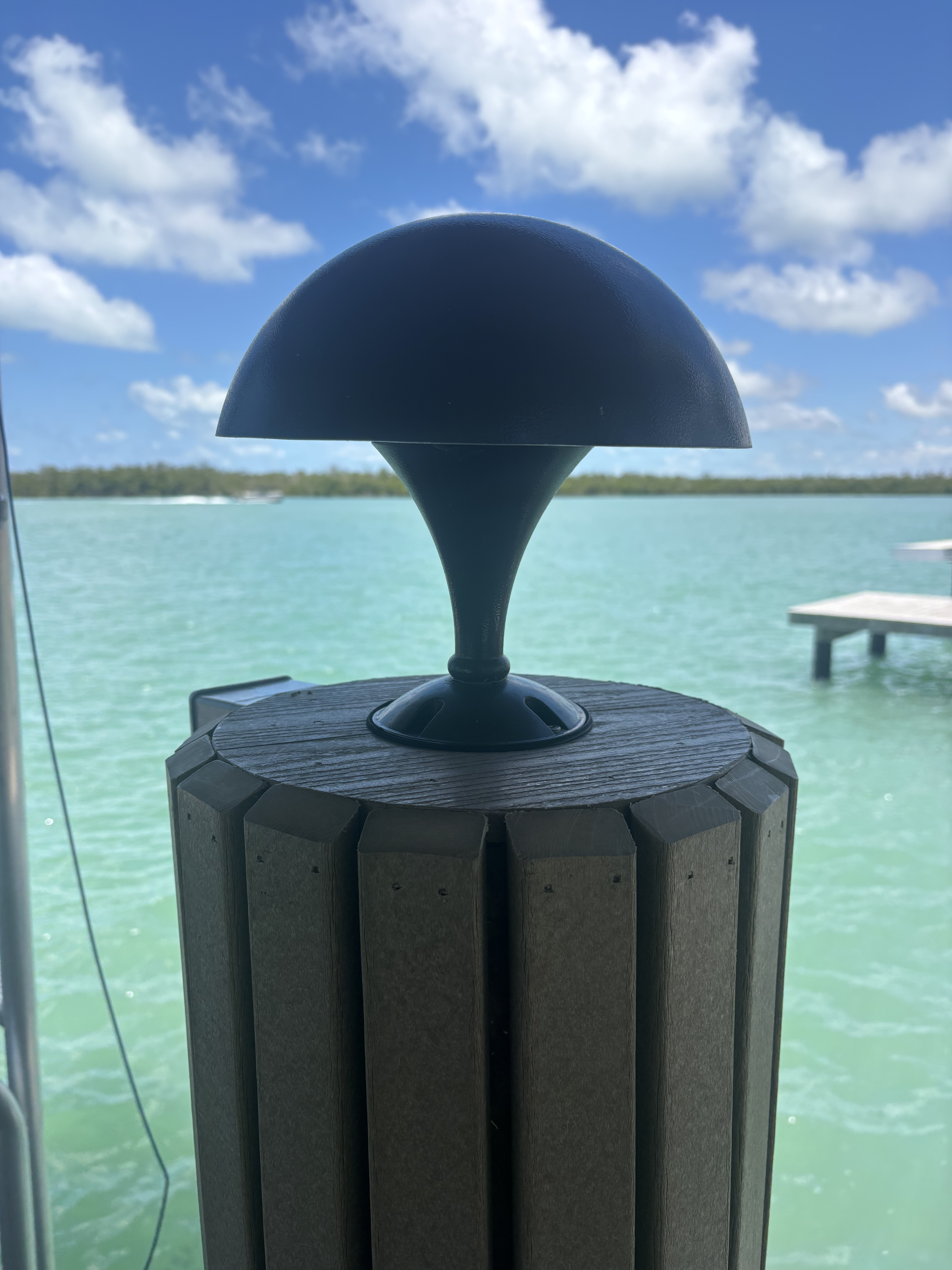 Piling-cap accent light — mushroom-style fixture that throws a warm glow across the dock and water.