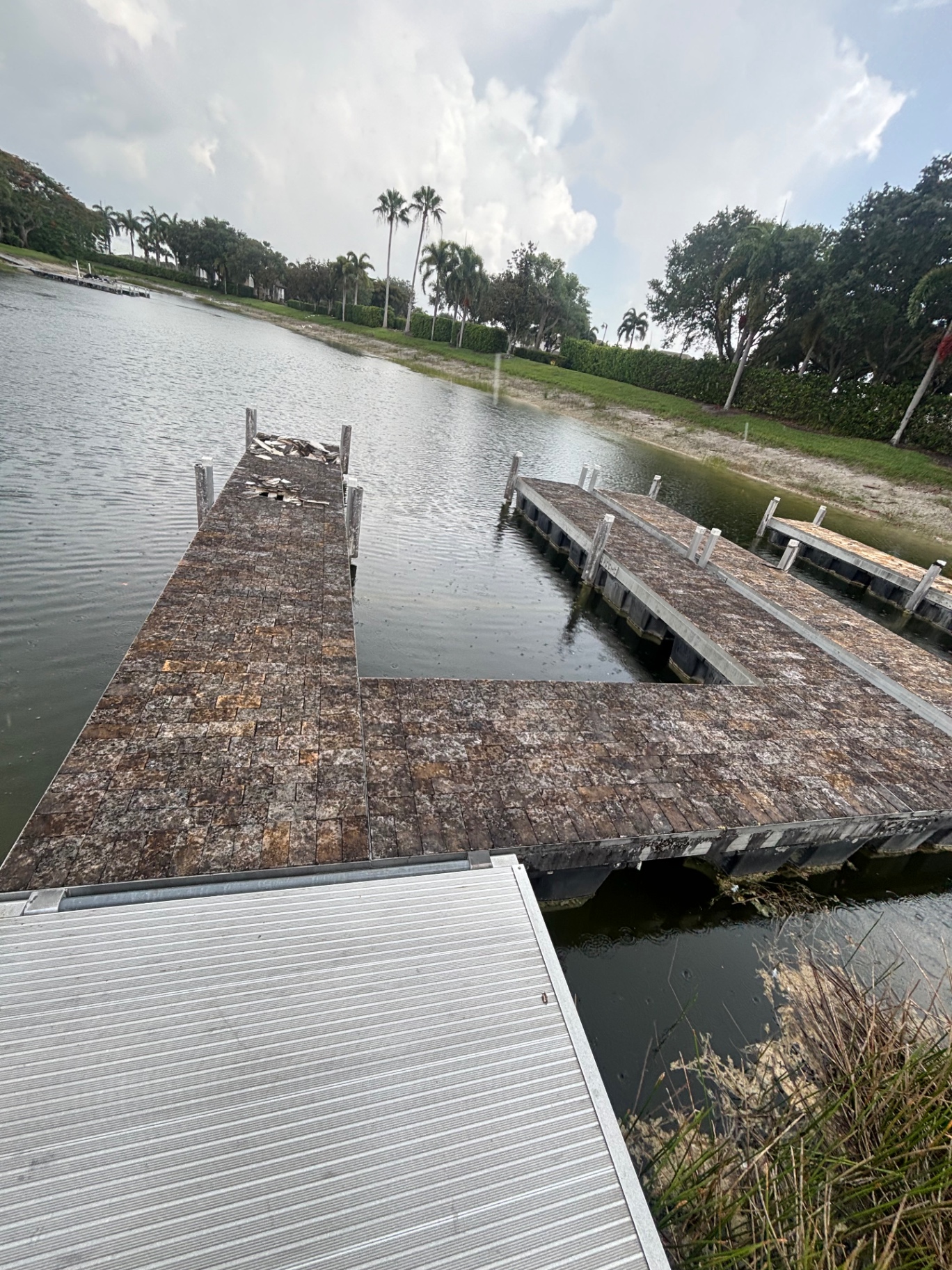 Wider view of the failing paver dock — cracked paver field, broken corners and a section of deck already caved in.