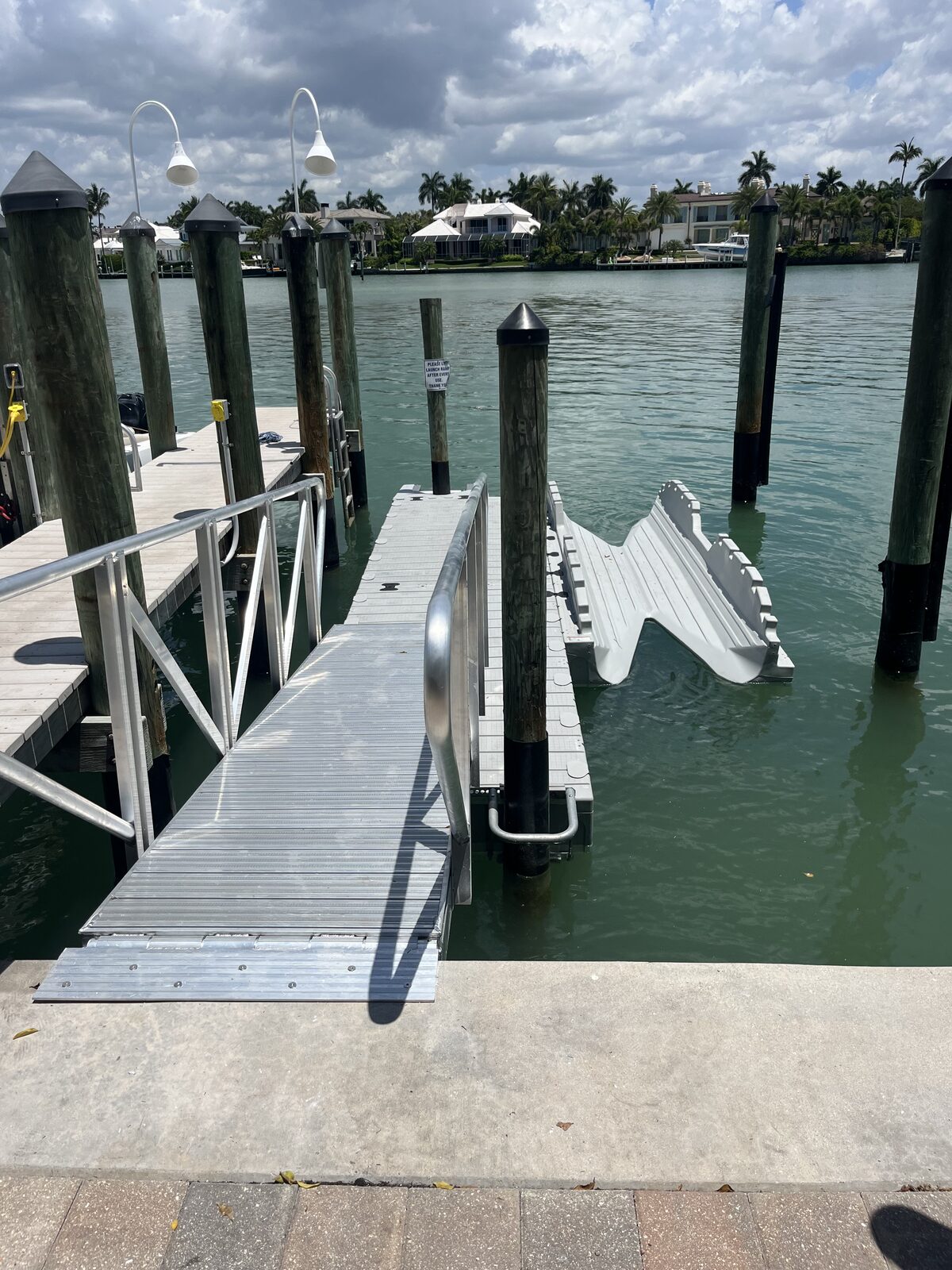 Floating dock with aluminum gangway and a molded PWC drive-on ramp on the side — clean, low-profile access straight off the seawall, no ladder needed.