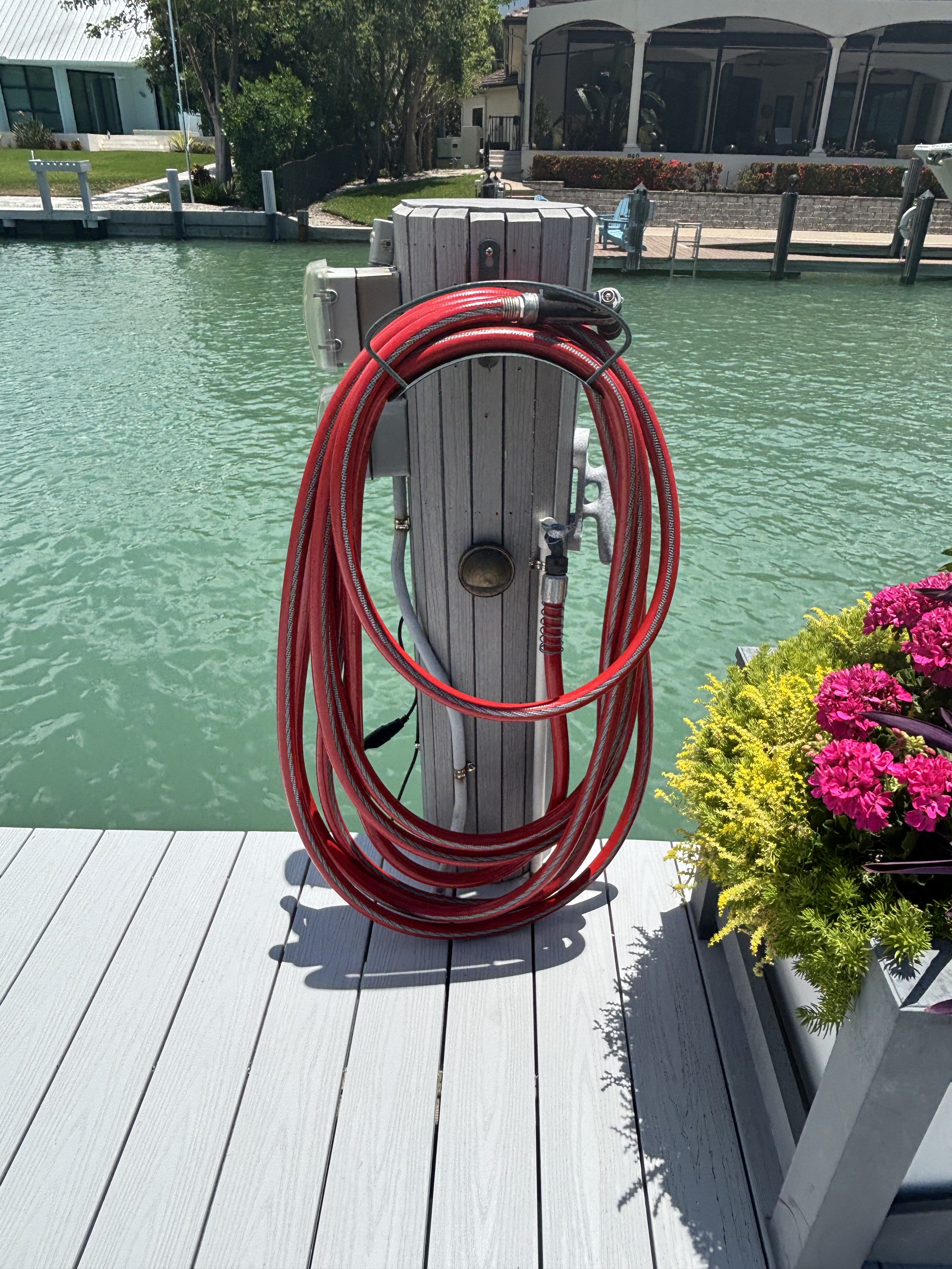 Piling-mounted hose holder keeping the washdown hose coiled, off the deck and out of the way.