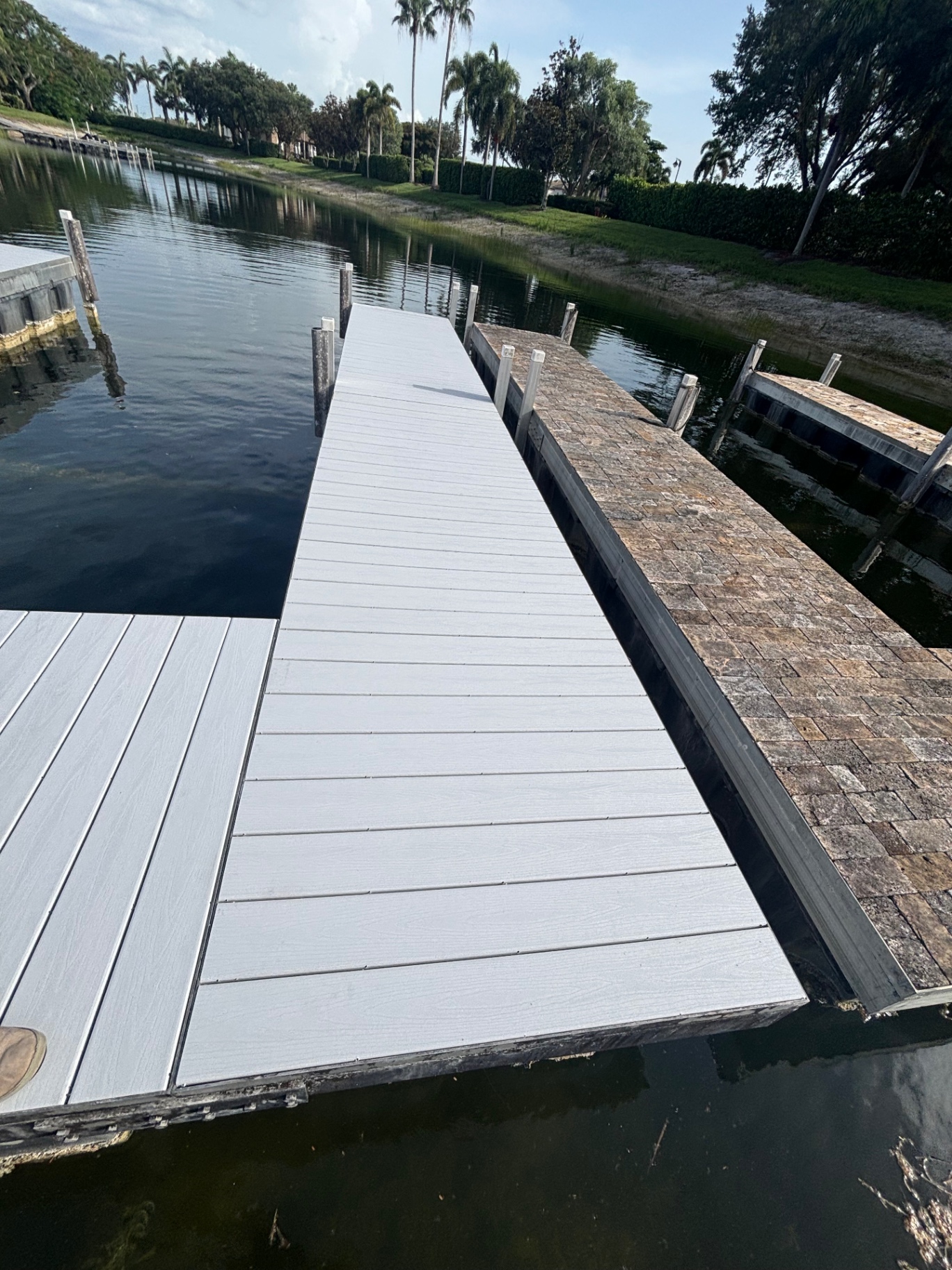 Fresh composite deck locked in — clean, flat, splinter-free surface with the old paver dock still visible next door for comparison.