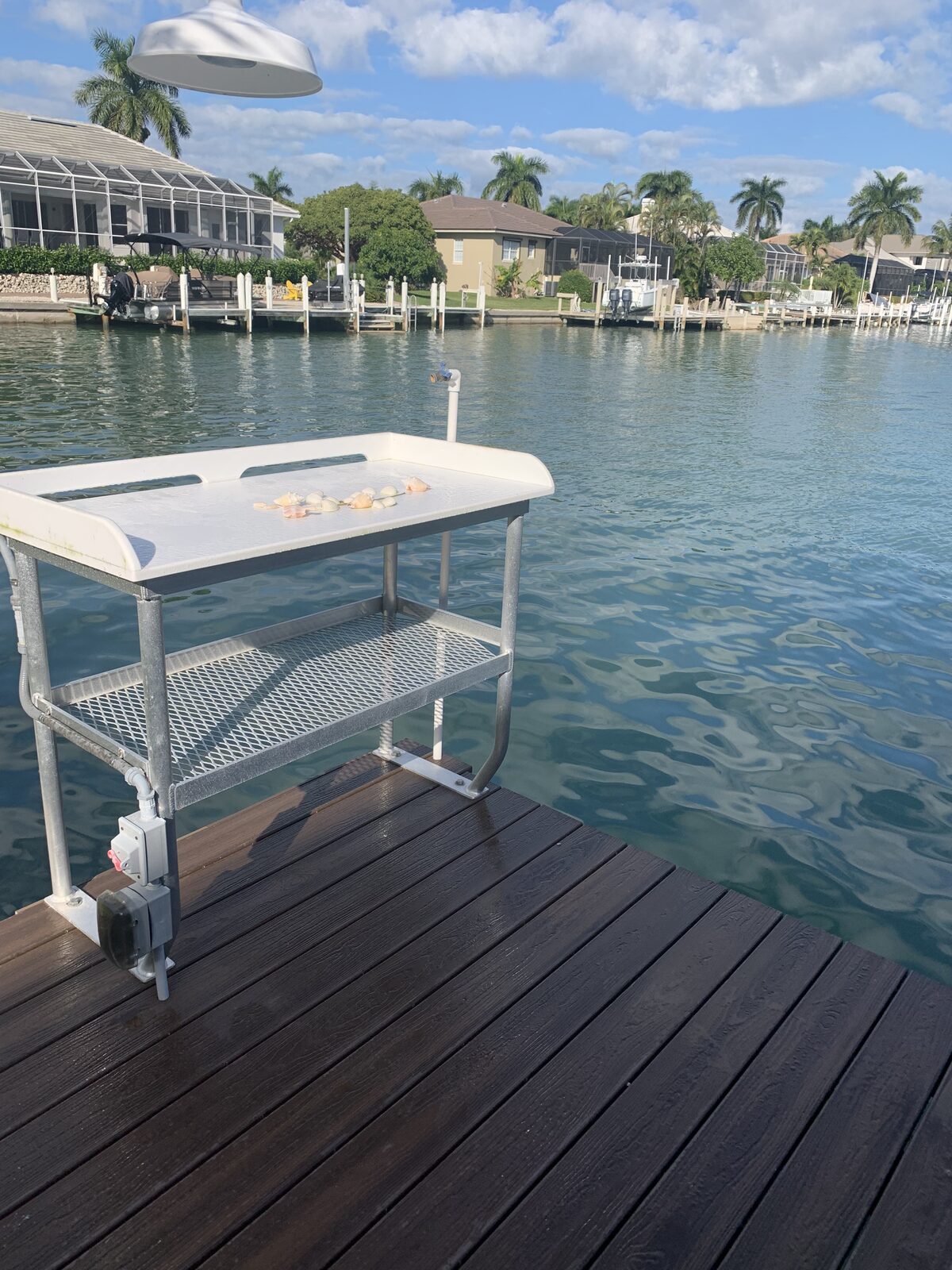 Aluminum fish cleaning station with hose bib, GFCI outlet and lower storage rack — plumbed straight to the dock so cleanup is a rinse and done.