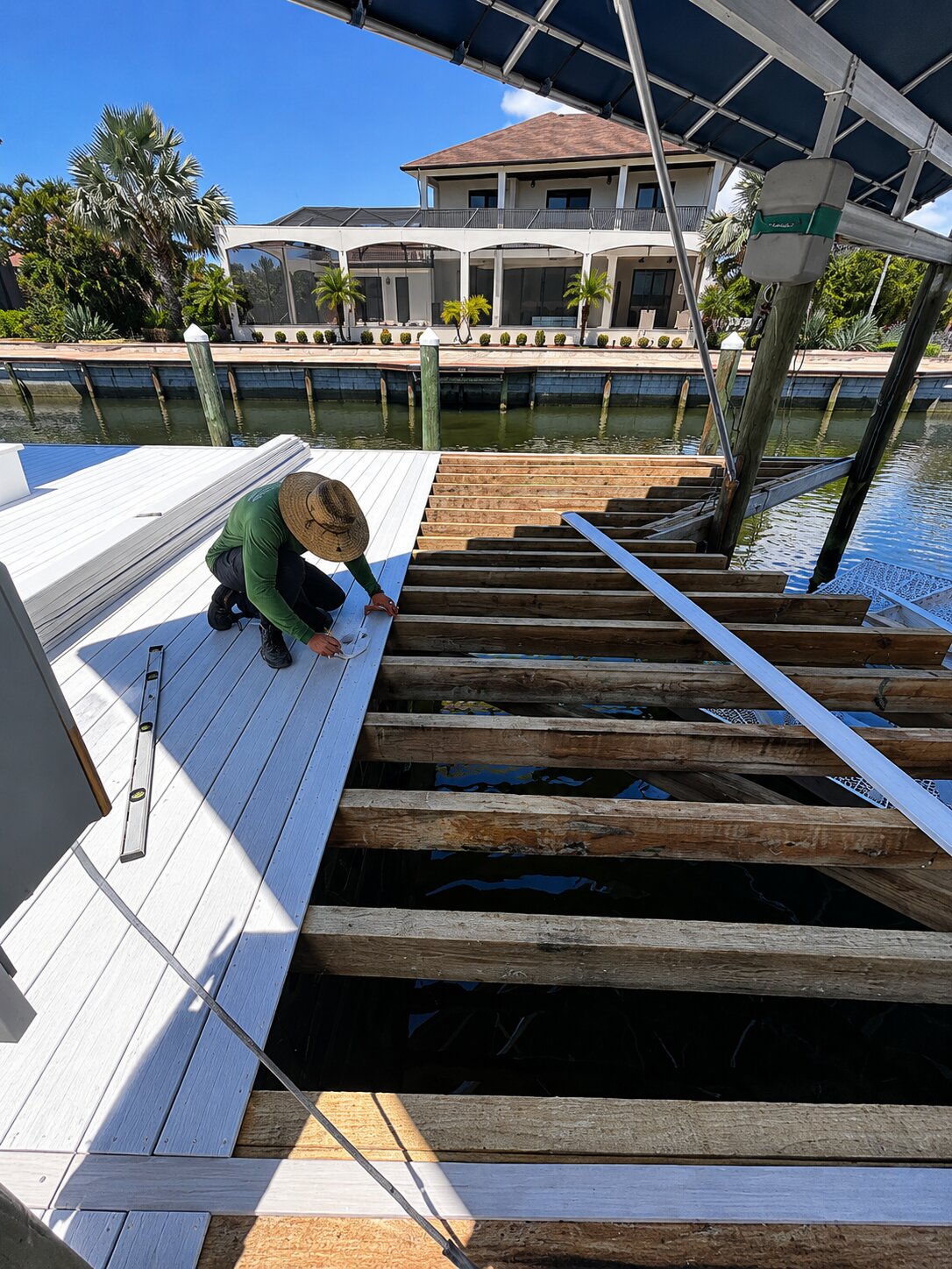 Fresh composite deck boards locked in over the new framing with hidden fasteners — finished dock reads as one clean surface.